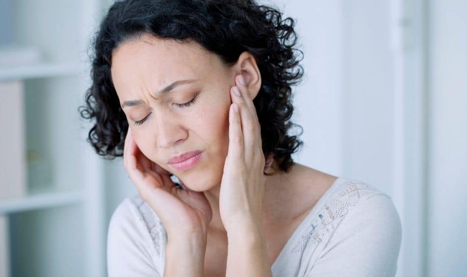 A woman holding her ears in discomfort
